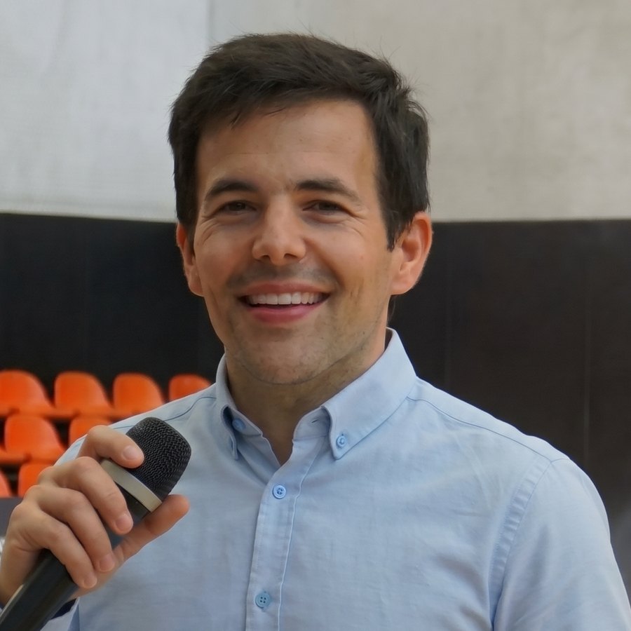 Carlos Villar sonriendo con un micrófono en una pista de baloncesto